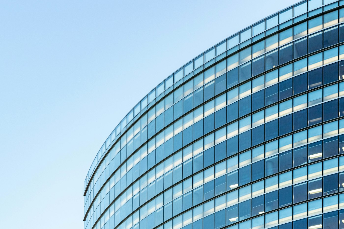 Curved glass office tower against a blue sky